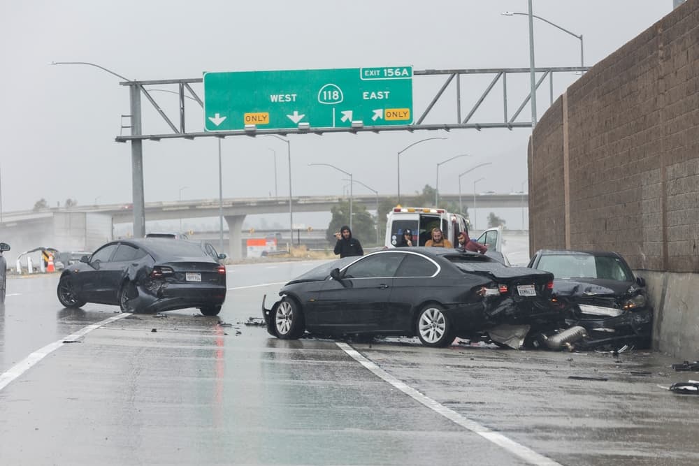 A three-car accident on the highway, with damaged vehicles at the scene.