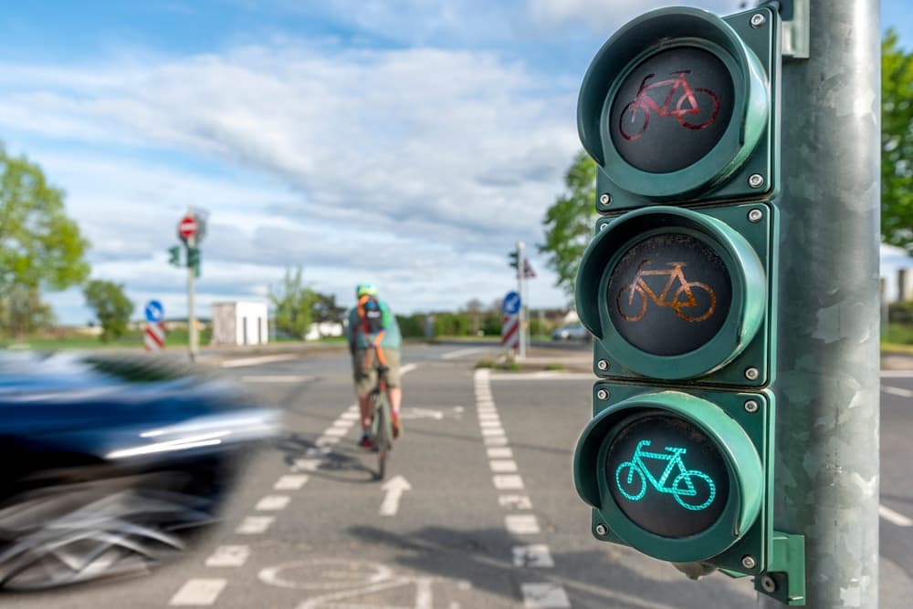 Near crash between a cyclist crossing a road at green phase and an approaching car