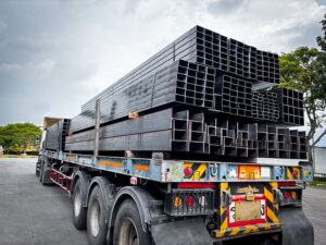 Group of square steel pipes and black steel construction products in a metal warehouse, ready for delivery to customers in the construction industry.