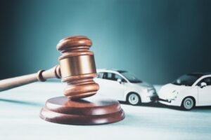 Model of a car next to a judge's gavel, symbolizing an accident lawsuit, insurance claims, or a court case related to a car accident.