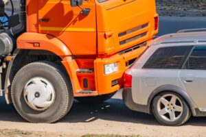 Car accident between an orange truck and a passenger car. 