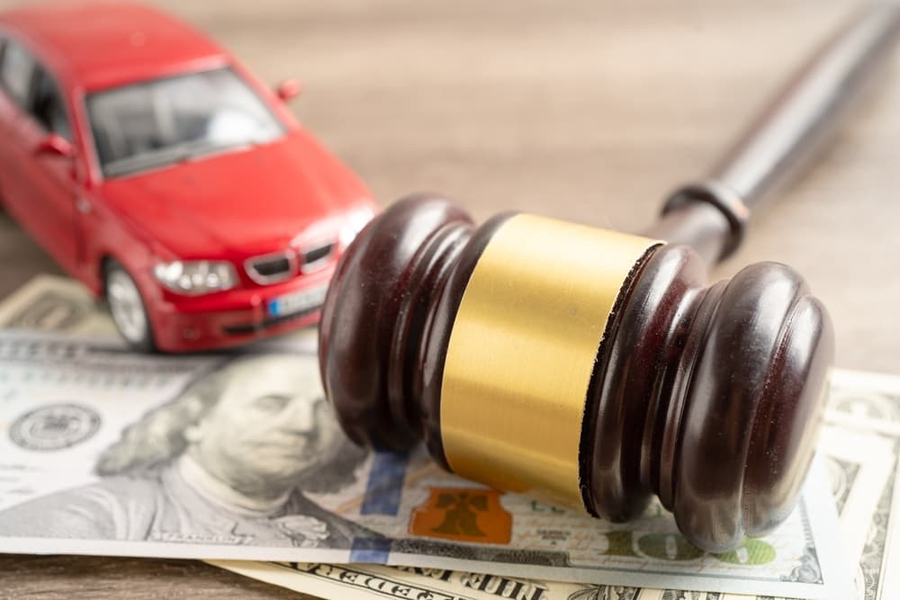 Hammer gavel judge and US dollar banknote money with car vehicle accident