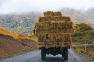 Weathered vintage truck driving on a mountainous road with improperly secured cargo, representing a traffic violation related to cargo safety.