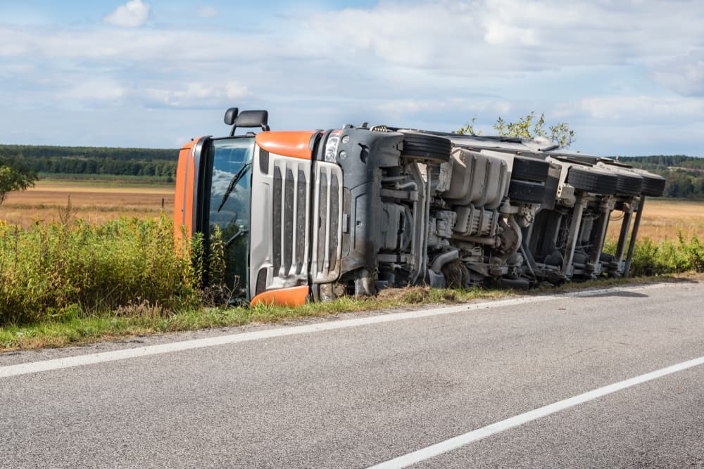 Overturned truck in roadside field, chassis exposed