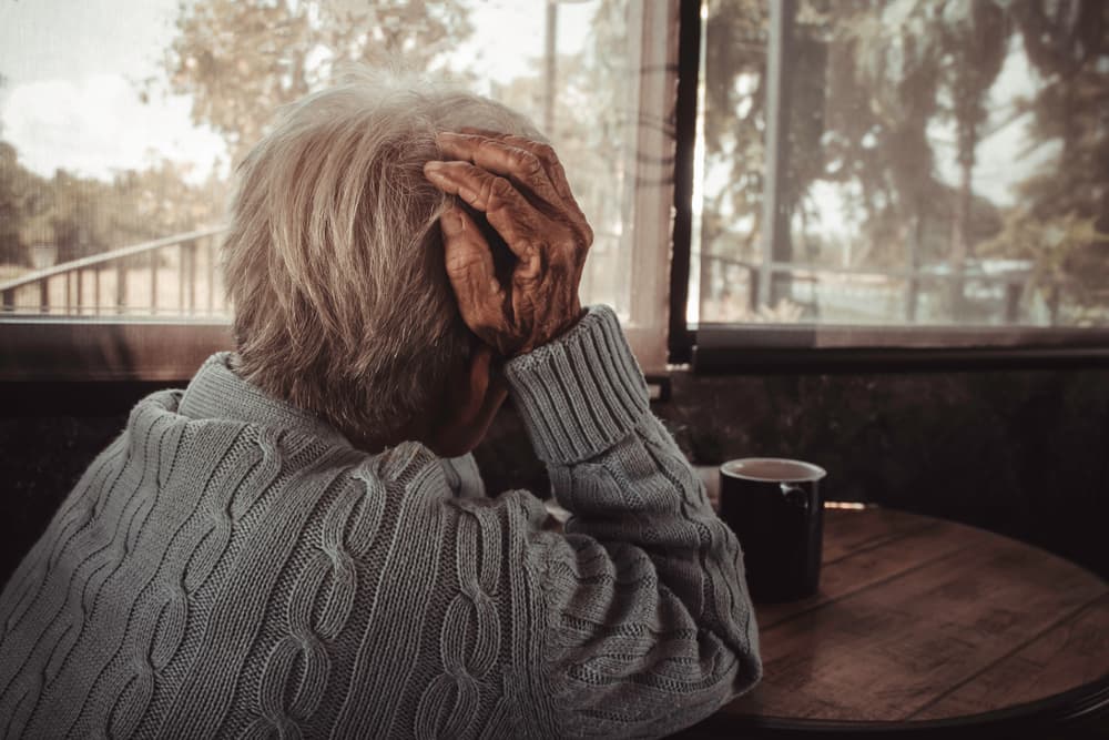 Older woman experiencing a headache, representing healthcare and emotional distress.